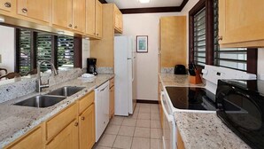 Una cocina con armarios de madera, un lavamanos doble, un refrigerador, una estufa y un microondas.