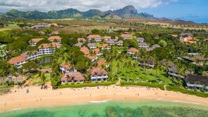 Une station balnéaire comprenant plusieurs bâtiments, une plage et des montagnes en arrière-plan.
