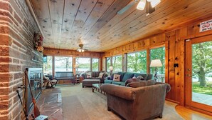 Una sala de estar acogedora con chimenea, asientos cómodos y ventanas amplias que ofrecen vistas al exterior.