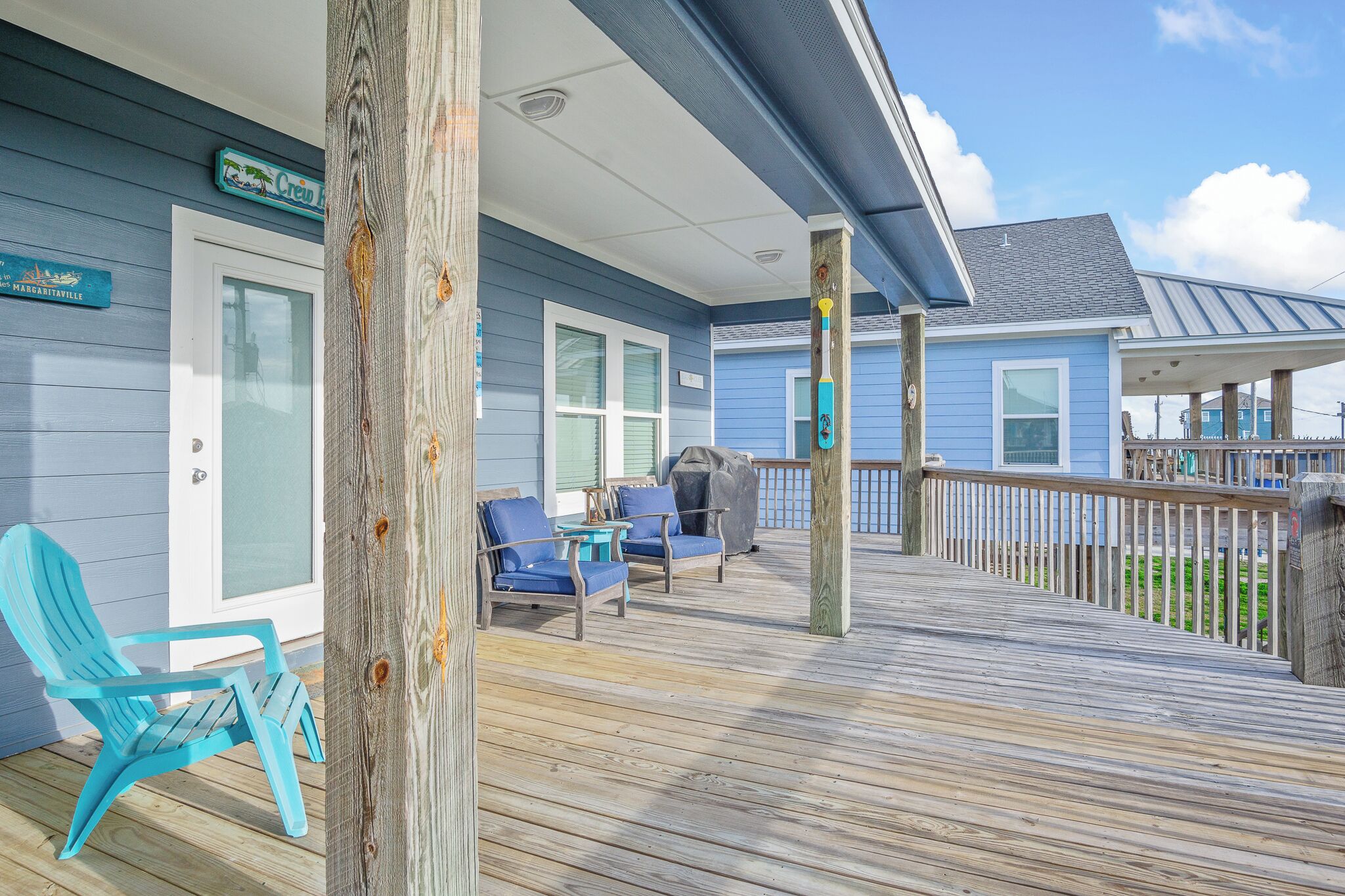 A wooden deck with outdoor seating, a covered area, and a view of the ocean.