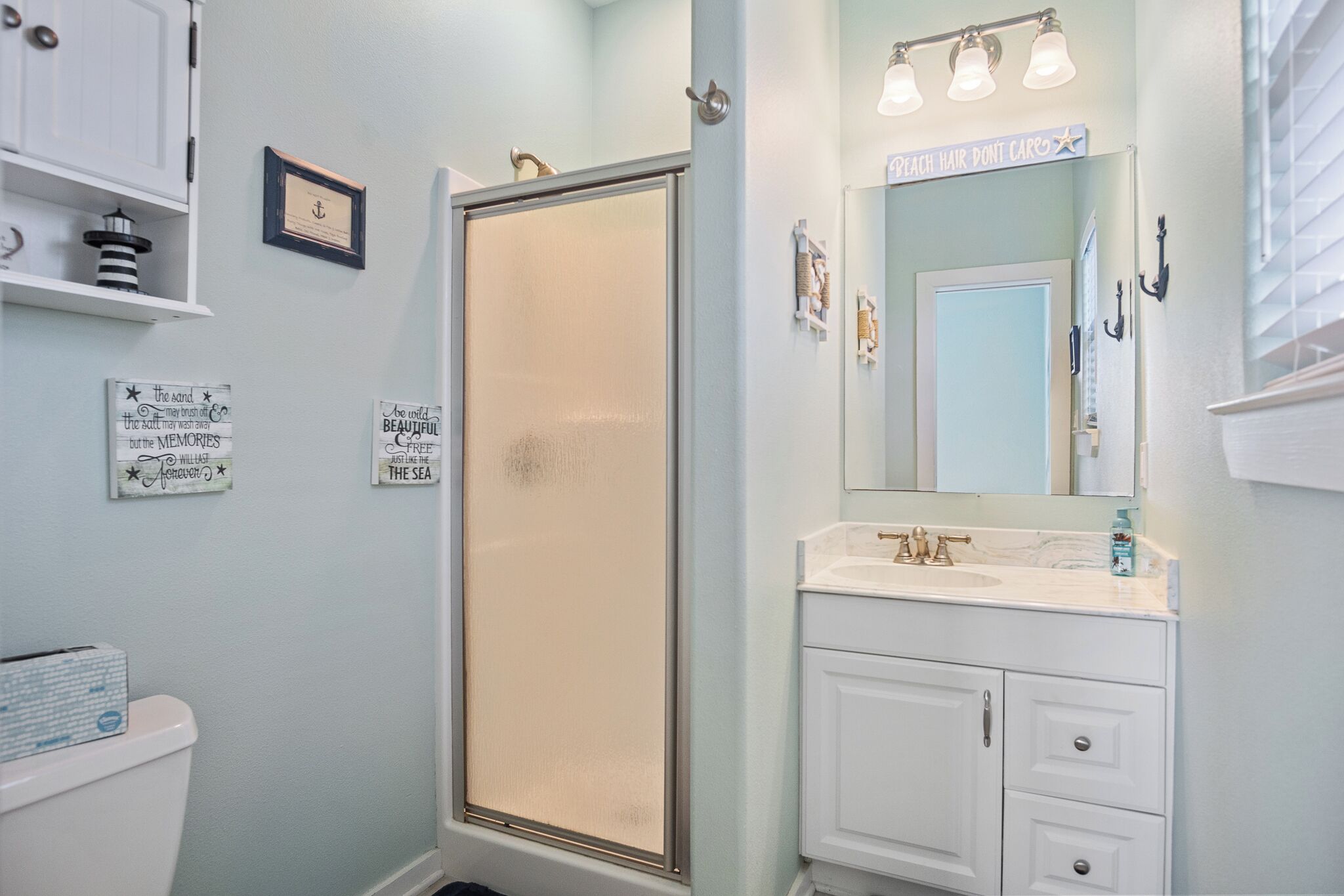 Une salle de bain équipée d’une douche, d’un lavabo, d’un miroir et de toilettes.