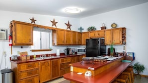 Una cocina con armarios de madera, un refrigerador negro, un microondas y un fregadero.