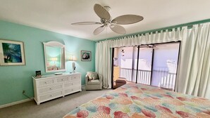 A bedroom with a bed, a dresser, a chair, a ceiling fan, and a view of a balcony. - Perfect family Gold-rated condo with easy access to pool and beach! (Saint Augustine)