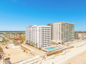 A multi-story hotel with a pool area and beach access.