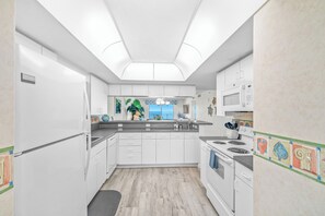 Une cuisine moderne avec des meubles blancs, un îlot central, un four à micro-ondes et une cuisinière.