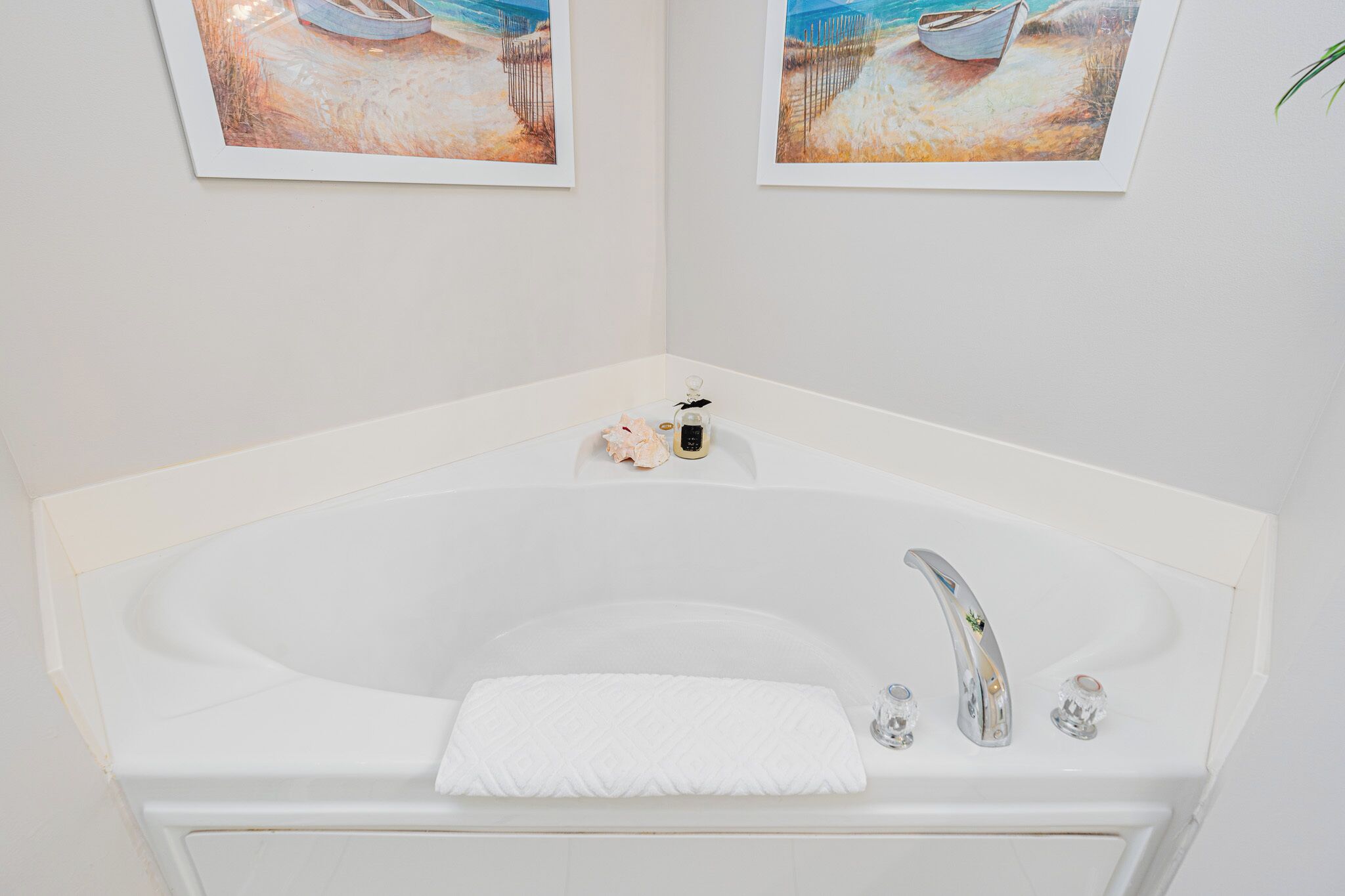 Une salle de bain moderne avec une baignoire sur pieds, un lavabo blanc et deux tableaux encadrés accrochés au mur.