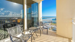 Ein Balkon mit Glastür, zwei Stühlen und einem Tisch.