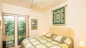Une chambre à coucher comprenant un lit, une chaise, une table de chevet, une décoration murale et une fenêtre avec des rideaux.