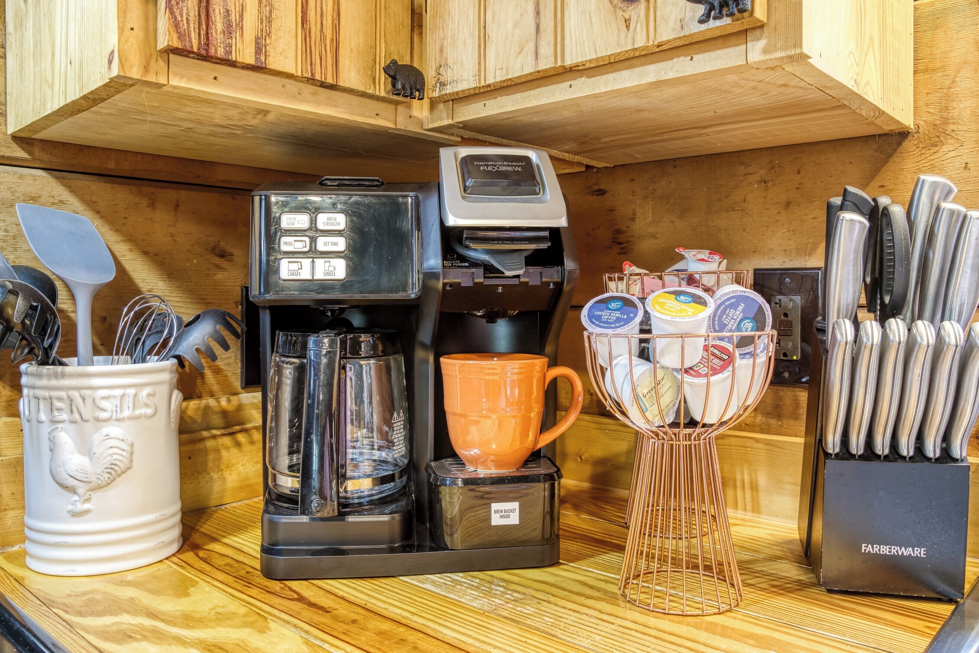 A kitchen counter with a coffee maker, a mug, utensils, and a knife block.