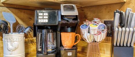 A kitchen counter with a coffee maker, a mug, utensils, and a knife block.