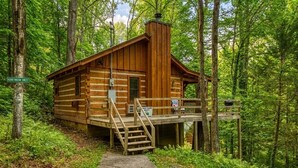 A wooden cabin with a porch and stairs, surrounded by forest. - Romance abounds!♥Hot Tub♥Whirlpool Bath♥Comm Pool♥Fire Table (Townsend)