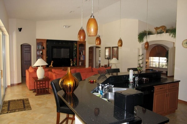 A spacious living area with a kitchen island, a fireplace, and a television in the background.