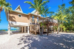 A beachfront hotel with a wooden exterior, a covered patio area, and a balcony overlooking the ocean.