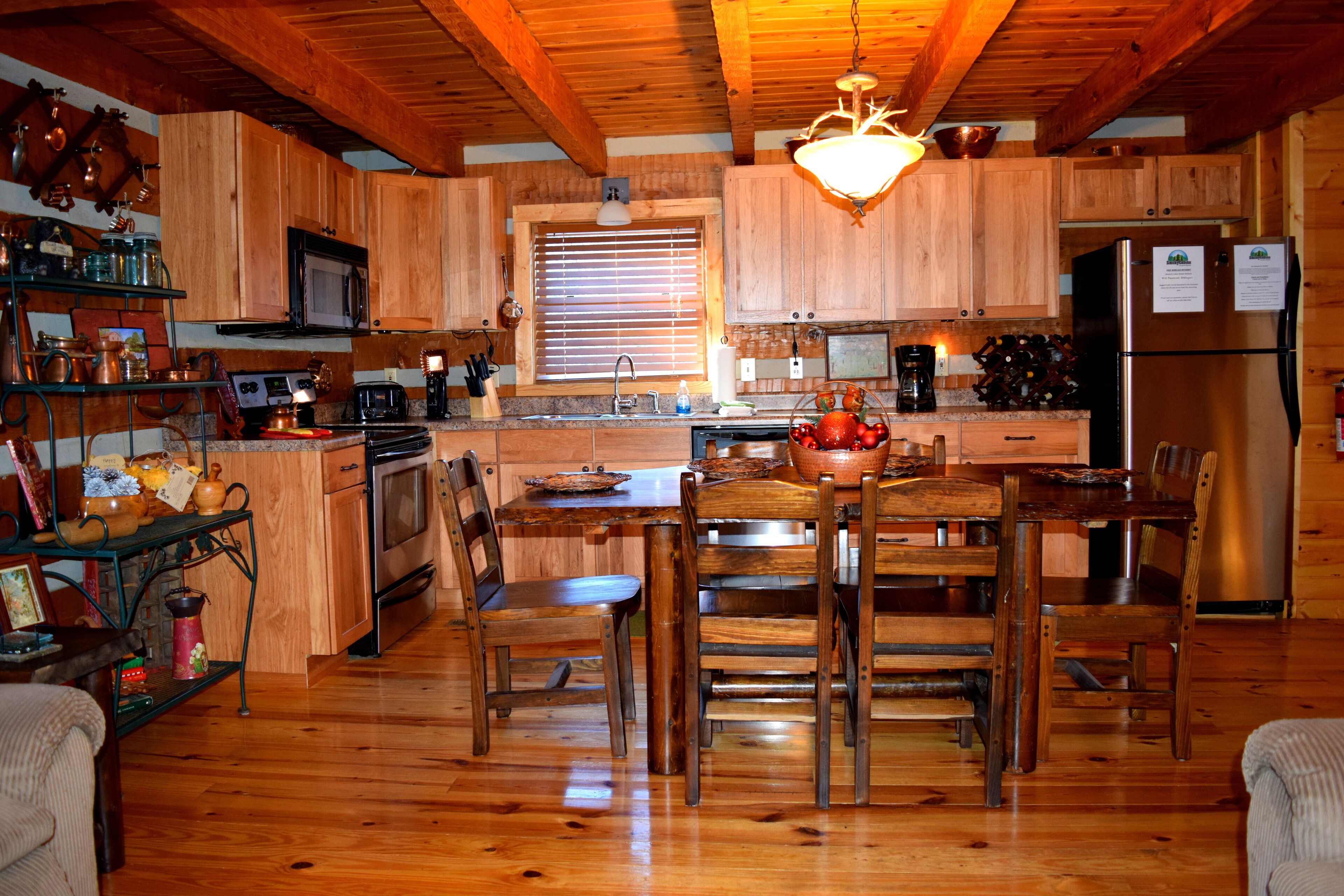 A wooden cabin-style kitchen with a central island, wooden cabinets, and a stainless steel refrigerator.