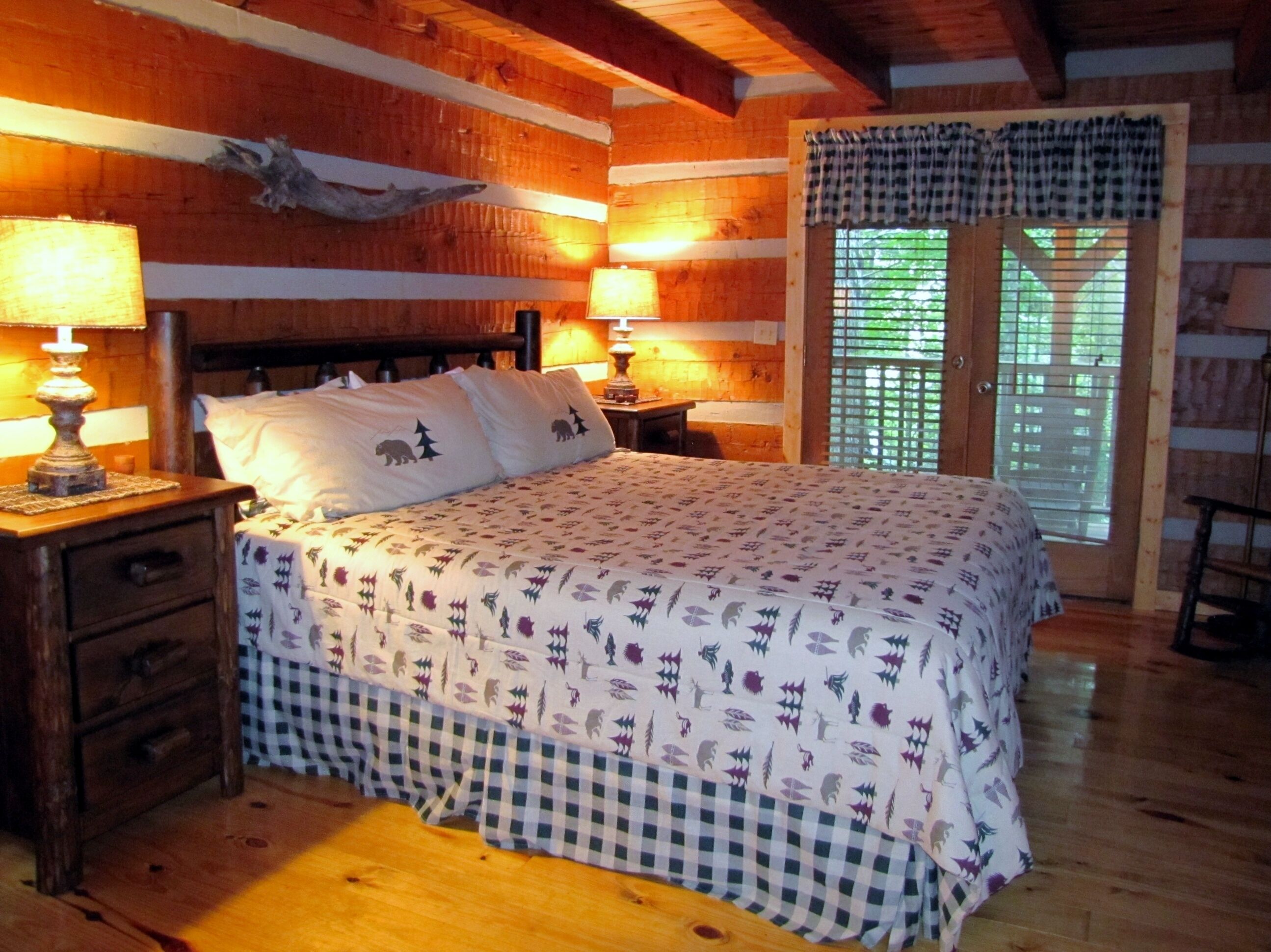 Une chambre confortable dans un chalet en bois, avec un lit, deux lampes de chevet, une table de chevet en bois et une fenêtre avec des volets.