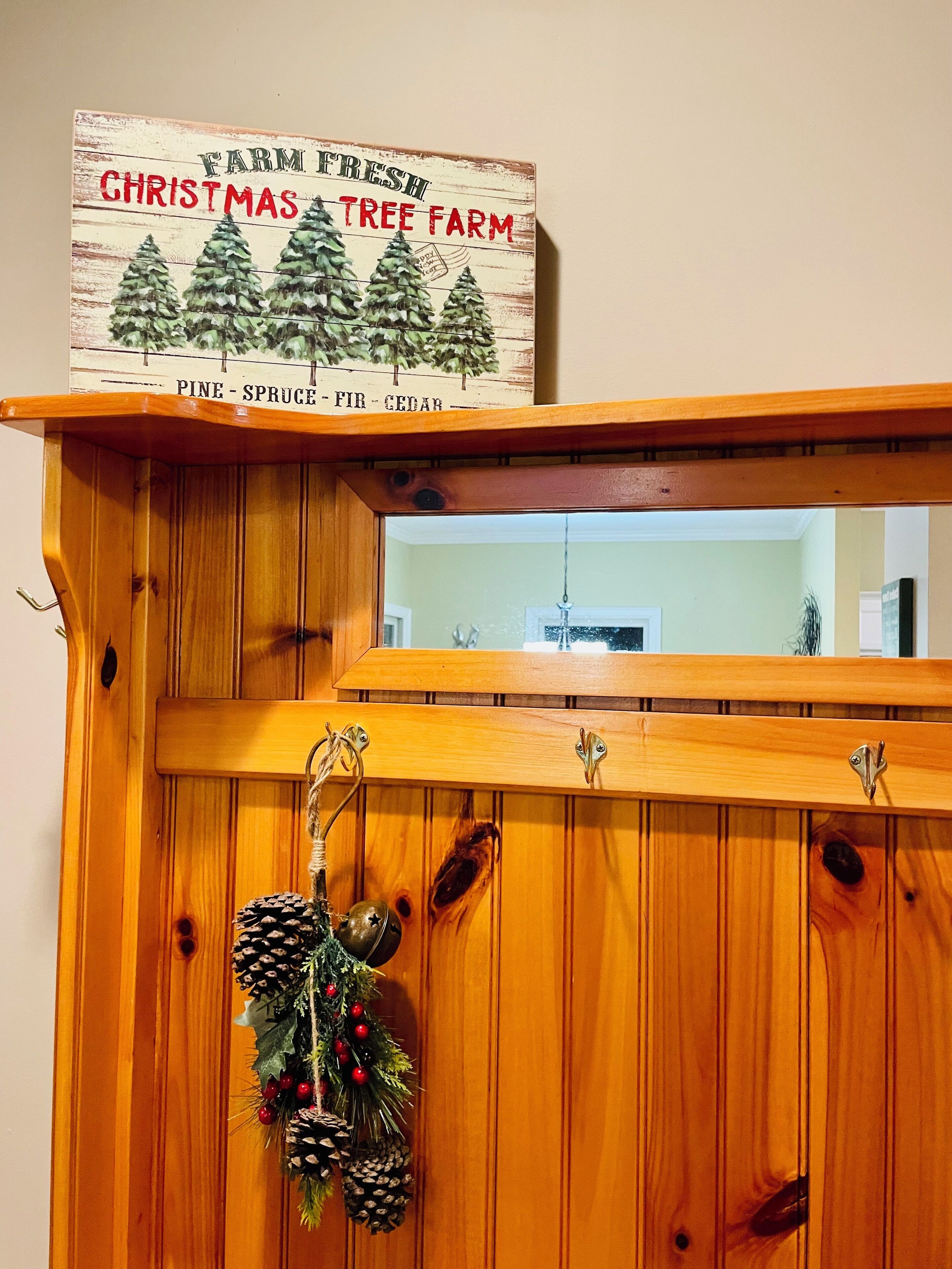 A wooden cabinet with a sign above it that reads "Farm Fresh Christmas Tree Farm" and lists pine, spruce, fir, and cedar.