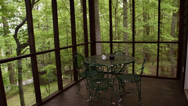 A wooden deck with a table and chairs, overlooking a forested area. - 3 bdrms, Bonfire Pit, Screened Porch, Mountain Shade (Townsend)