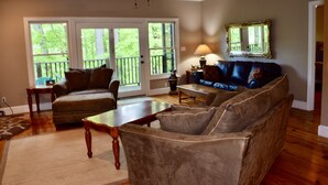 A living room with a sofa, armchairs, a coffee table, and a lamp. There is a large window with a view of trees. - 3 bdrms, Bonfire Pit, Screened Porch, Mountain Shade (Townsend)