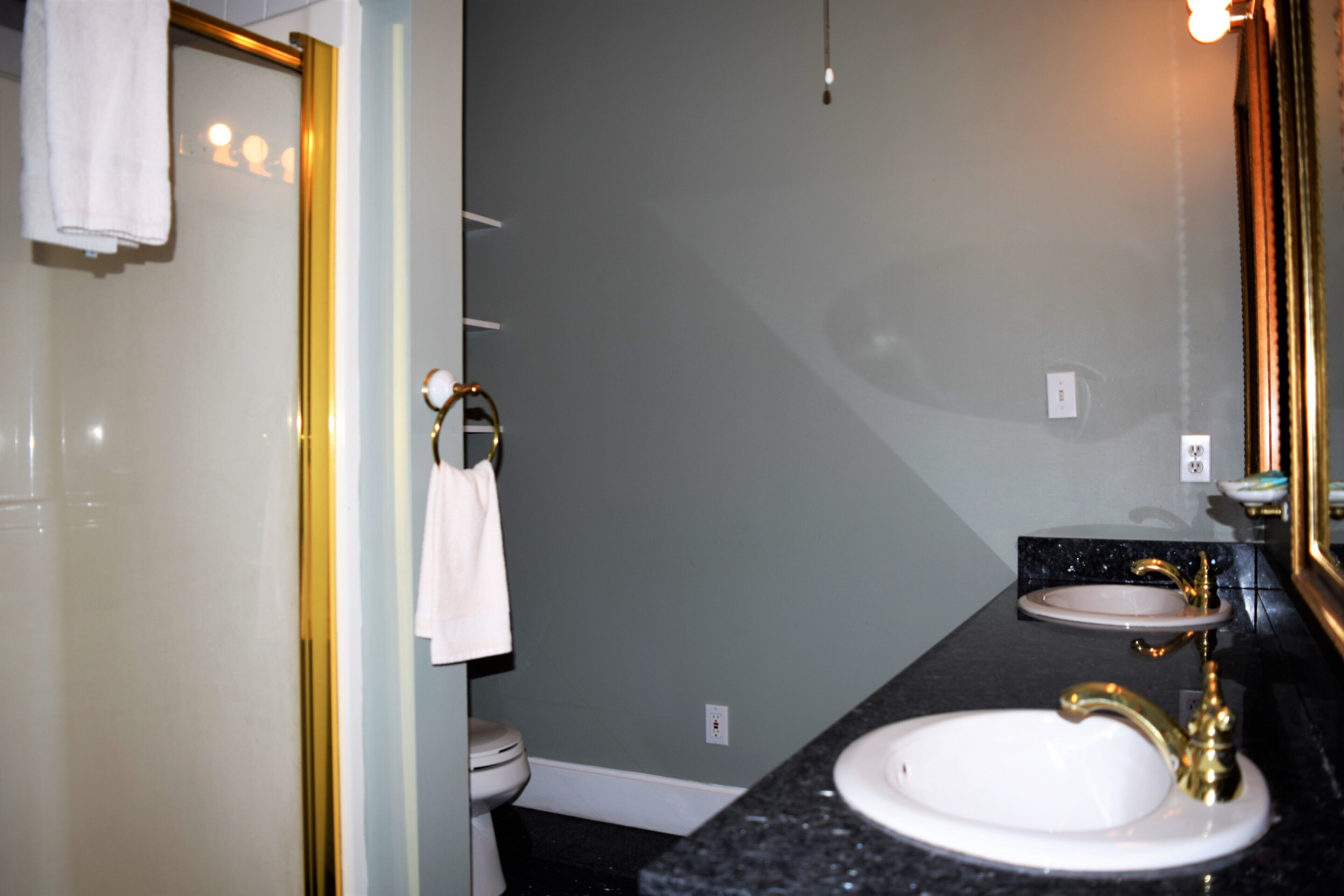 A bathroom with a white sink, a gold faucet, and a mirror with a gold frame.