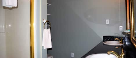 A bathroom with a white sink, a gold faucet, and a mirror with a gold frame.