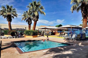 Relax by the pool surrounded by lush palm trees and a shaded pavilion.