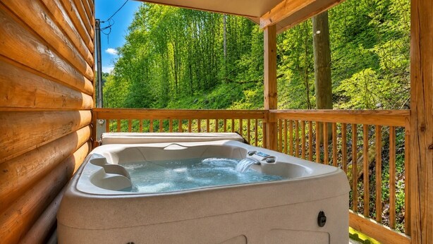 A wooden cabin with a hot tub on a deck overlooking a forest. - Hot Tub❅Wood Fireplace❅King Bed❅Cozy - BEAR'S DEN (Townsend)