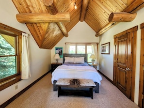 Cozy retreat with a large bed, bedside tables, and a bench, set amidst a rustic interior.