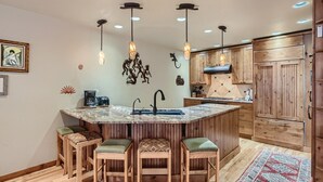 A kitchen with a central island, wooden cabinets, pendant lights, and a coffee maker. - Beautiful half duplex home, recently remodeled with garage and private hot tub!! (Frisco)