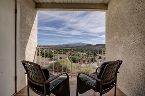 A balcony with two chairs facing a view of a residential area and mountains. - Las Palmas Resort #318 | All-Inclusive Amenities (Saint George)
