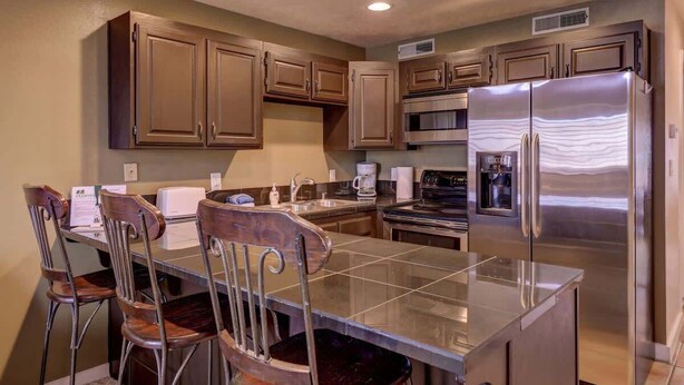 Una cocina con una isla central, electrodomésticos de acero inoxidable y armarios de madera.