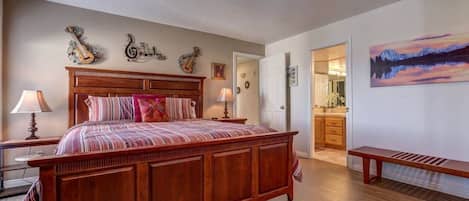 Een slaapkamer met een houten bed, een bankje en een schilderij aan de wand.