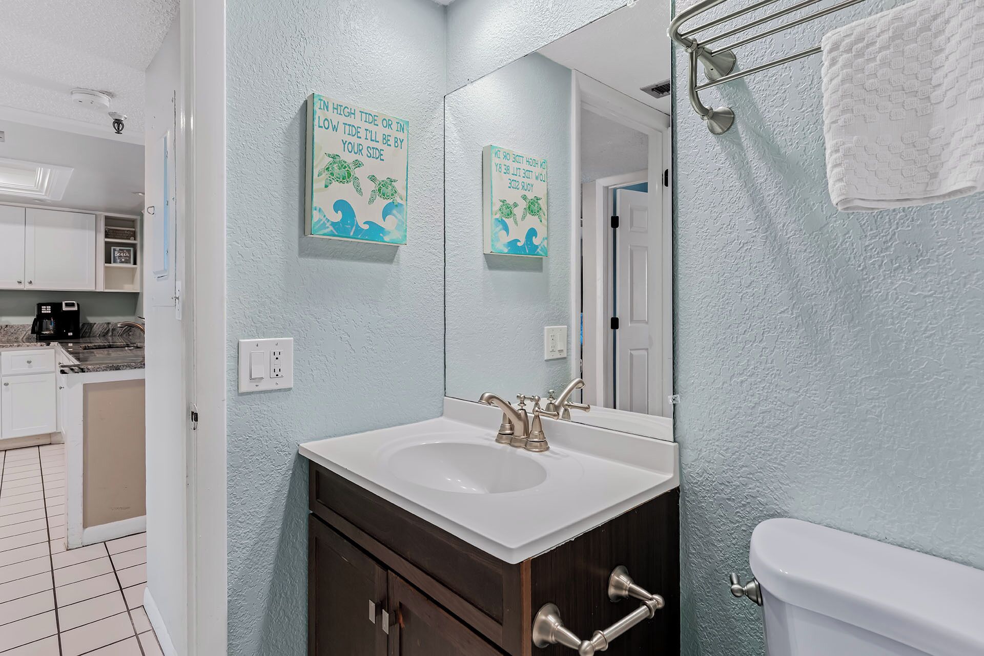 A bathroom with a white sink, dark wooden cabinet, and a white toilet. There are two wall-mounted mirrors above the sink.