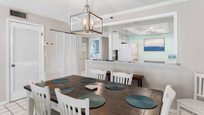 Un comedor con una mesa de madera, sillas blancas y una lámpara colgante.