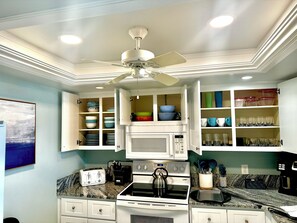 Une cuisine équipée d’un four à micro-ondes encastré, d’une cuisinière et d’un ventilateur de plafond.