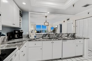 The bright open kitchen flows seamlessly into your living space, where ocean breezes and stunning blue skies await just beyond the windows. Sleek granite counters and modern appliances make meal prep a breeze.