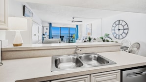 Cocina moderna con un lavamanos empotrado, ventilador de techo y un espejo grande que refleja un balcón con vistas.