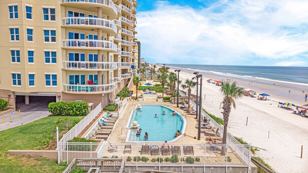 A hotel with a pool, beach, and ocean view.