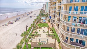 A beachfront hotel with multiple balconies, a pool area, and a beach view.