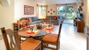 Un coin repas avec une table en verre, des chaises en bois et un ventilateur de plafond.
