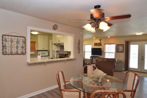 Relax in this spacious living area with a dining table and four chairs, a ceiling fan, and a flat-screen TV.