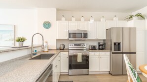 A modern kitchen with white cabinets, stainless steel appliances, a granite countertop, and a small sink. - Bright condo with amazing bay views. WIFI + Parking (Sunny Isles Beach)