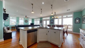 Enjoy cooking in this well-equipped kitchen with a central island, white cabinetry, and a large window offering a view of the outdoors.