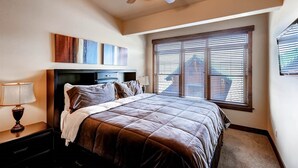 A bedroom with a bed, a ceiling fan, a nightstand, a lamp, and a window with blinds. - Beautiful 2 bedroom plus den close to Main Street, Frisco! (Frisco)