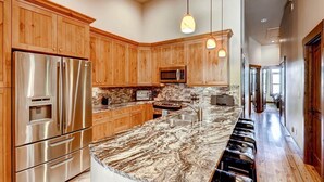 A modern kitchen with wooden cabinets, stainless steel appliances, and a marble countertop. - Beautiful 2 bedroom plus den close to Main Street, Frisco! (Frisco)