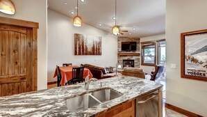 A modern kitchen with a marble countertop, wooden cabinetry, and pendant lighting. - Beautiful 2 bedroom plus den close to Main Street, Frisco! (Frisco)