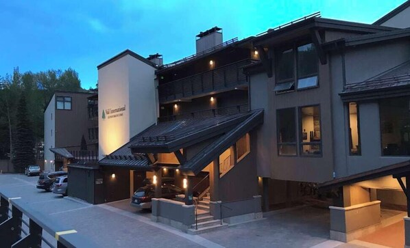 Un immeuble à plusieurs étages doté d’une entrée imposante, d’un espace extérieur couvert et d’un escalier menant aux étages supérieurs.