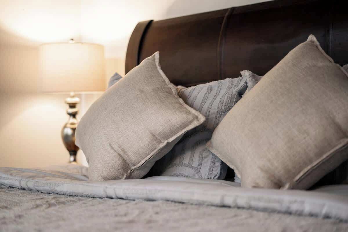 Een bed met kussens en een lamp op de achtergrond.