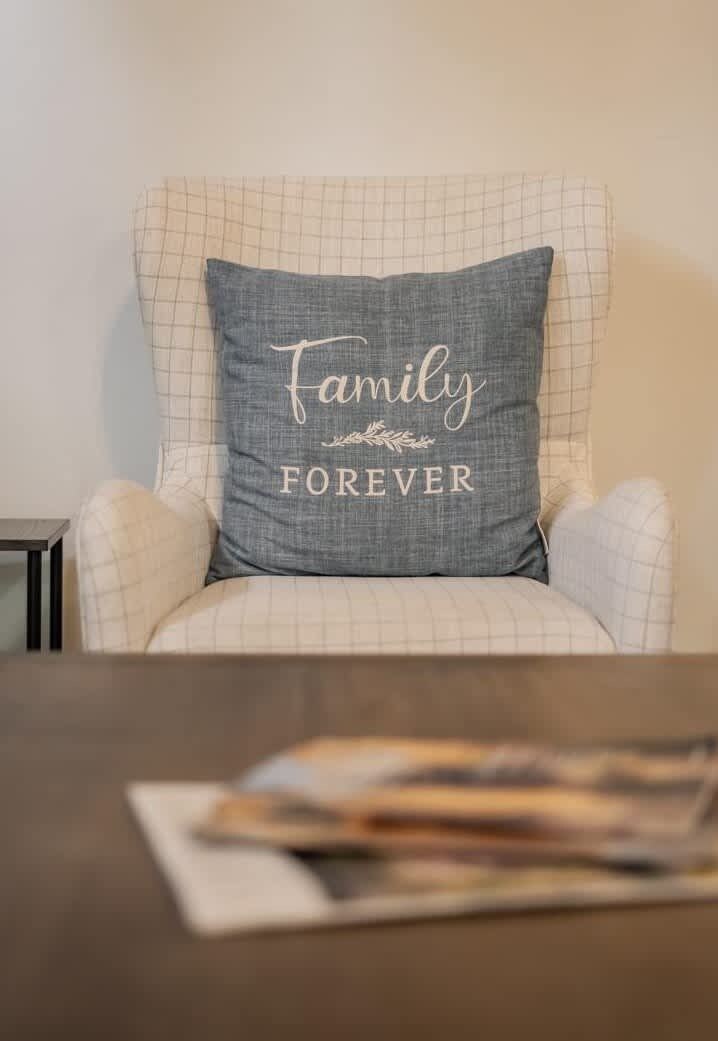A chair with a pillow that reads 'Family Forever.'
