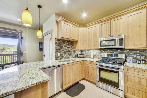 Enjoy cooking in this well-equipped kitchen with a large window offering a view of the surrounding landscape.