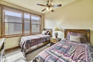 Two single beds with matching headboards and footboards, positioned near a window with a view of the surrounding neighborhood.